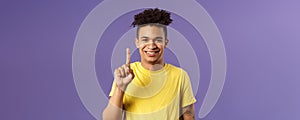 Close-up portrait of funny young teenager, guy picking nose showing index finger and giggle, gagging over his own joke