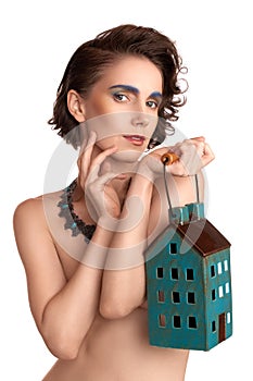 Close-up portrait, girl architect with color make-up holding a model house on a white background