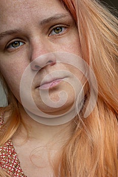 Close-up portrait of a girl with orange hair without makeup and skin retouching.