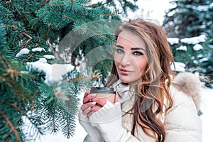 Close-up portrait, girl in warm jacket, winter background of spruce and snow. The emotions of pleasure and enjoyment are