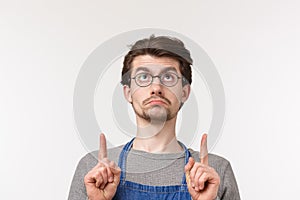 Close-up portrait of gloomy handsome bearded young male student start career as bartender, wear paron and glasses