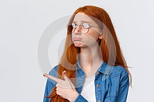 Close-up portrait gloomy and sad pouting cute redhead girl with lovely blue eyes, wear glasses, sulking and sobbing sad