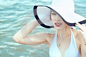 Close up portrait of gorgeous elegant glam lady hiding the half of her face behind the wide brim hat