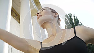 Close-up portrait of graceful ballerina dancing outdoors. Live camera follows movement of slim young Caucasian woman