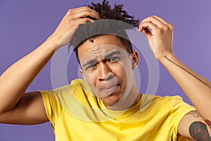 Close-up portrait of grimacing young focused guy looking in mirror at his haircut, need call his stylish or hairdresser