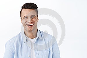 Close-up portrait of handsome adult man with beaming smile, looking camera satisfied, feel upbeat and enthusiastic