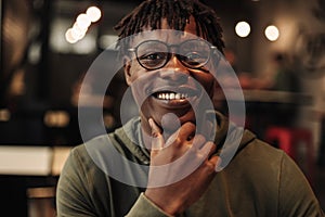 Close-up portrait of handsome African American man wearing glasses, smiling and looking at camera