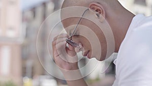 Close-up portrait of handsome bald thoughtful middle eastern man sitting in front of the building. Leisure outdoors