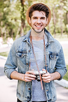 Close-up portrait of a handsome guy holding camera outdoors