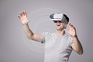 Close up portrait of handsome male in grey t-shirt, experiencing virtual reality using VR headset glasses. Young man wearing goggl