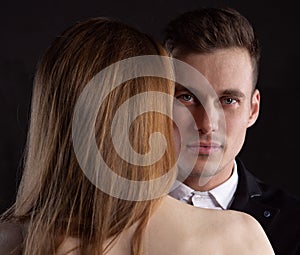 Close up portrait of a handsome man looking at the camera from behind the naked back of a sexy girl