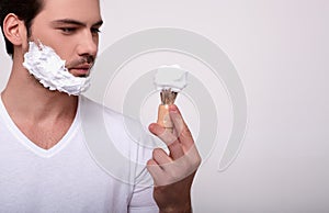 Close up portrait of a handsome man with shaving foam on his face isolated over white background