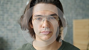 Close-up portrait of handsome man wearing glasses looking at camera at home alone