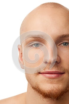 Close-up portrait of handsome young bald man with unshaved face, blue eyes, clear spotless skin isolated against white