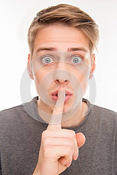 Close up portrait of handsome young man gesturing to make silence