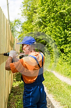 Close up portrait of handy carpenter fixes wooden fence