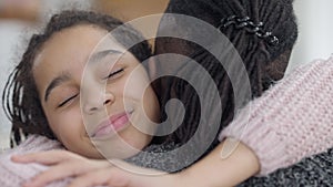 Close-up portrait of happy African American teen girl hugging man smiling looking at camera. Joyful beautiful teenage