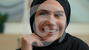 Close up portrait happy Arabian muslim Islamic woman in black hijab indoors cheerful smiling female face dental toothy