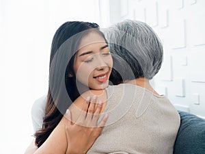 Close-up portrait of happy Asian beautiful daughter or grandchild embracing her senior, mother or grandparent.