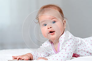 Close-up portrait of a happy baby lying on the bed. Copy space. The concept of parenthood and family planning