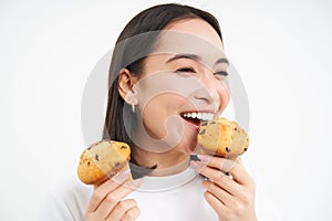 Close up portrait of happy, beautiful smiling woman, eating pastry cupcake, likes bakery, white background