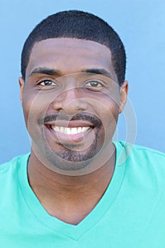 Close up portrait of a happy black man in his 20s with a perfect smile isolated on a blue background