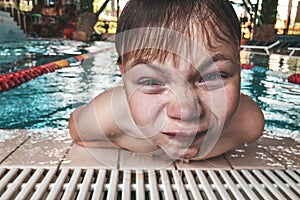 Close-up portrait of happy boy in the swimming pool at aquapark. Cute child having fun enjoyable time on vacation. Looking at cam