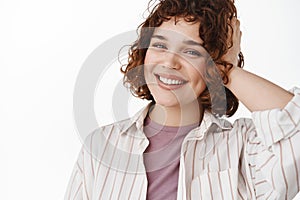 Close up portrait of happy candid girl with relaxed pose, cheerful white smile and stylish curly short hairstyle