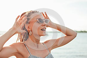 Close up portrait happy carefree young woman with african braids in sunglasses enjoy life on beach, summer vacation time
