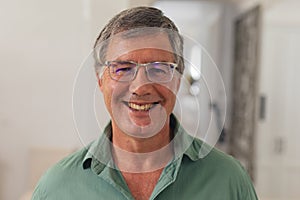 Close-up portrait of happy caucasian senior man in eyeglasses at home