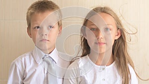 Close-up portrait of happy children with blue eyes and blond hair in school uniform. Boy and girl preschoolers on wind.