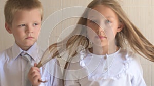 Close-up portrait of happy children with blue eyes and blond hair in school uniform. Boy and girl preschoolers on wind.