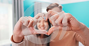 Close up portrait happy couple faces looking through joined fingers making heart shape. St Valentines