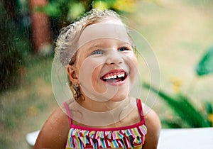 Close up portrait of happy cute little girl enjoy summer rain