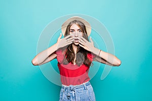 Close up portrait of a happy excited young woman in beach hat with mouth open looking at camera over blue background