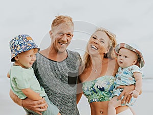 Close up portrait of happy family spending time on the beach. Father and mother holding sons. Cute baby boys. Smiling parents.