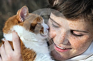 close-up portrait of happy freckled girl and red cat