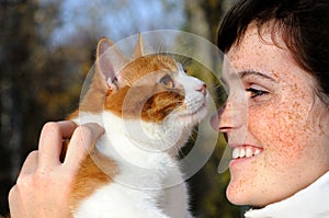 close-up portrait of happy freckled girl and red cat