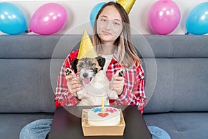 Close-up Portrait of a happy girl with her funny pet dog Jack Russell Terrier dog celebrating her birthday at home. Design by cake