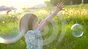 Close up portrait of happy little cute boy having fun with soap bubbles in park. Little child playing with parents