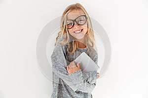 Close-up portrait of happy little girl in glasses hugging a book
