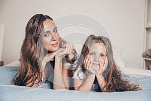 Close up portrait of happy loving family lying relaxing enjoying in bedroom together. Mother and her cute preschool daughter child