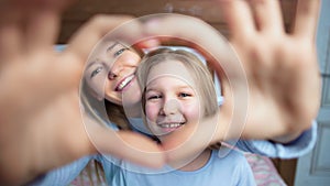 Close-up portrait of happy mother and daughter showing gesture love heart by hands