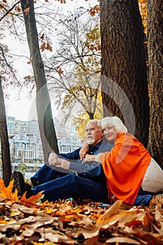 Close up portrait of a happy old woman and man in a park in autumn foliage