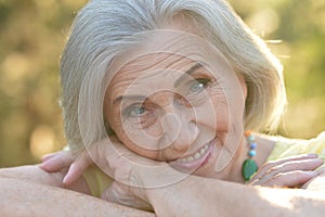 Close up portrait of happy older woman standing outside in summer