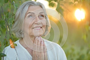 Close up portrait of happy older woman standing outside in summer