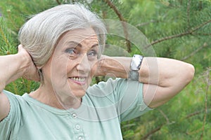 Close up portrait of happy older woman standing outside in summer