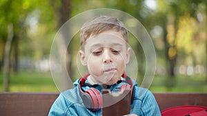 Close-up portrait of happy relaxed boy biting chocolate bar and chewing delicious dessert. Cheerful cute Caucasian child