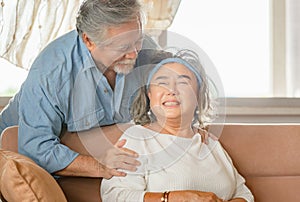 Close up portrait of happy senior asian couple hugging in living room