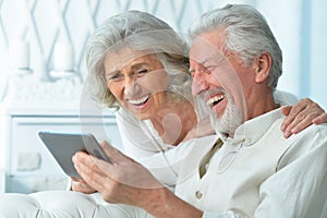 Close up portrait of happy senior couple using tablet